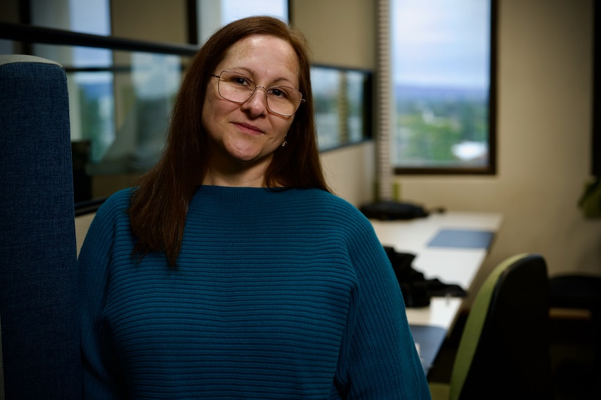 a woman in green jumper wearing glasses