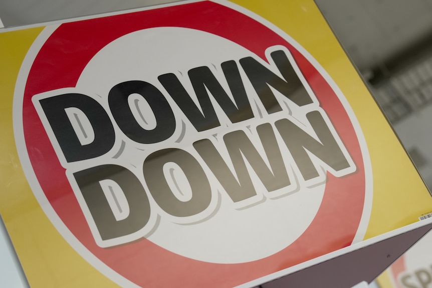 A close up of a red and yellow promotional sign with the words Down Down.