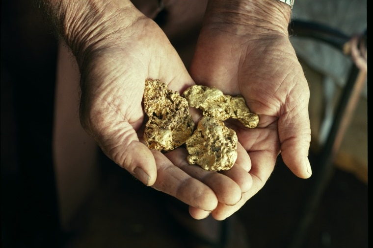 nuggets of gold in the palms of two hands.