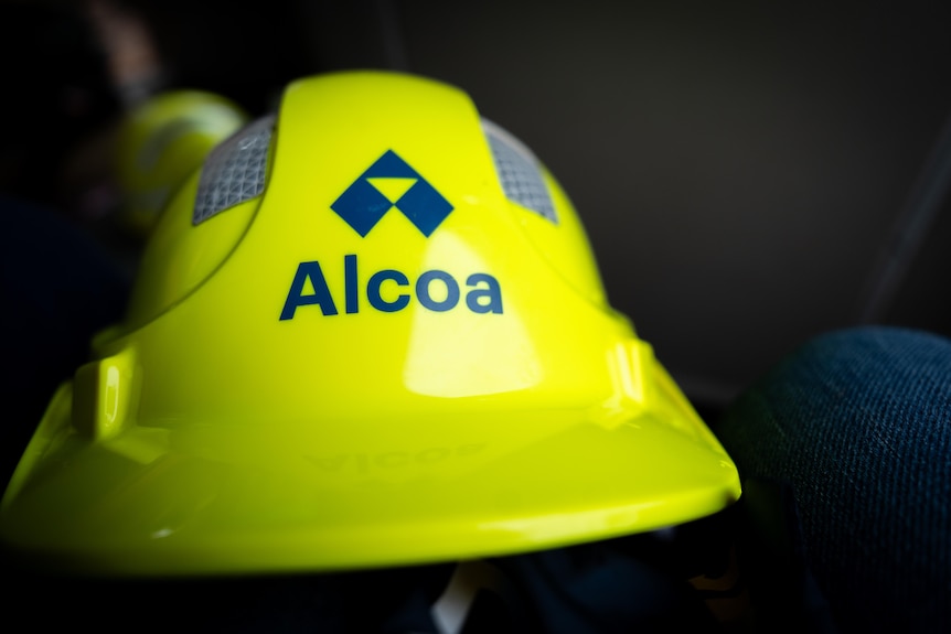 A hi-vis yellow hard hat with Alcoa printed on the front.