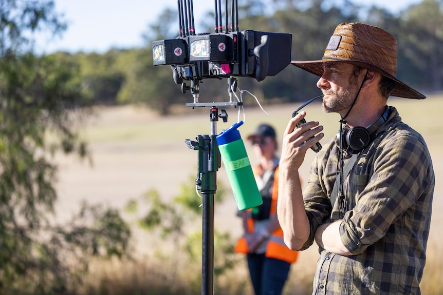 A movie director stands next to a camera.