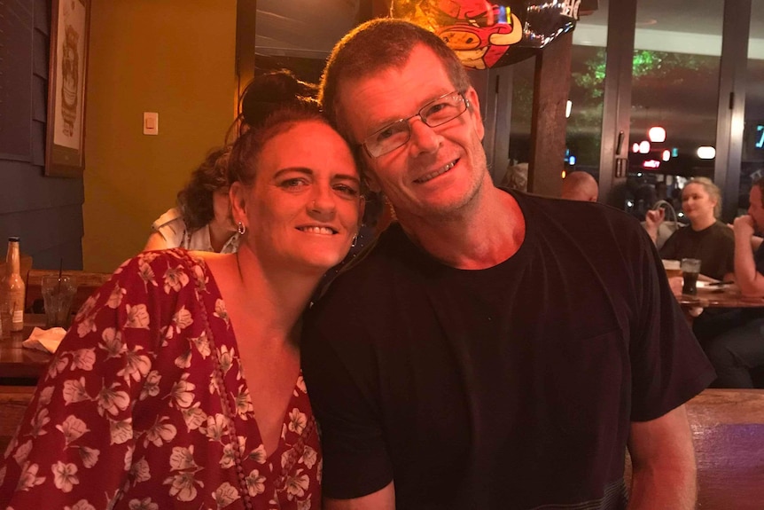 Kylie Truswell-Mobbs and David Mobbs smile while sitting next to each other with their heads together at a restaurant.