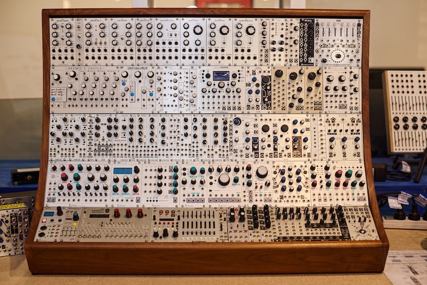 A very old, box-like synthesiser with hundreds of knobs and buttons.