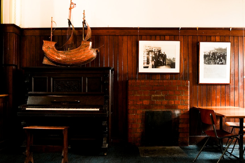 An old piano with a model ship on top