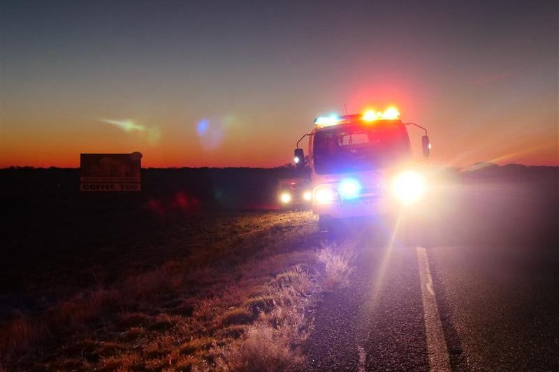 A rural fire truck drives through a paddock at dusk.