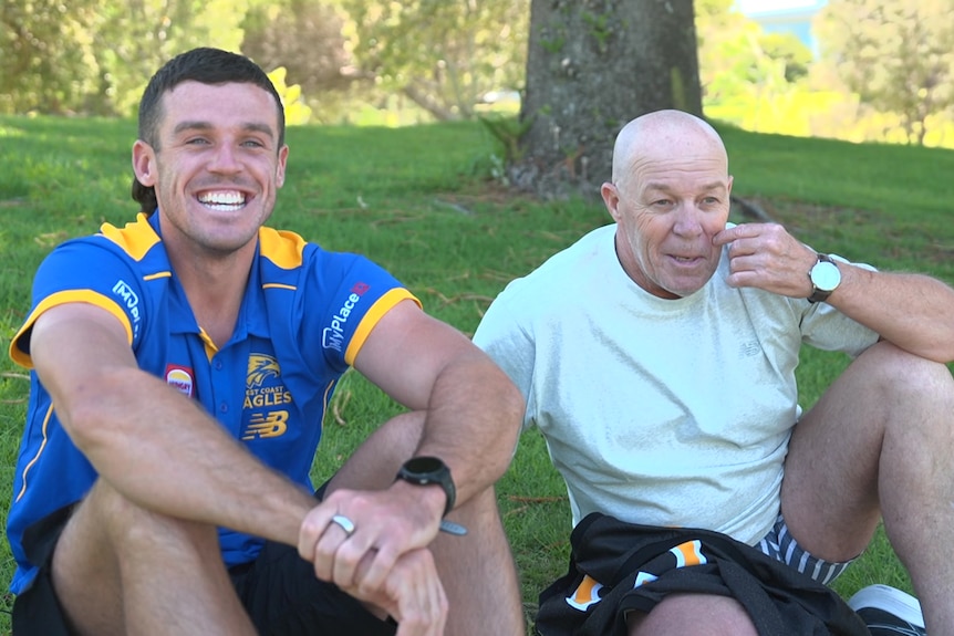 Jake and Chris Waterman standing side by side, Jake wearing a WA guernsey and Chris holding his up. 