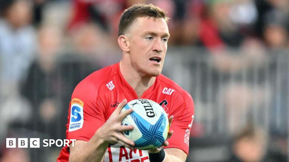 Dallas McLeod holds the ball in two hands in front of him while on the pitch during a match for Crusaders