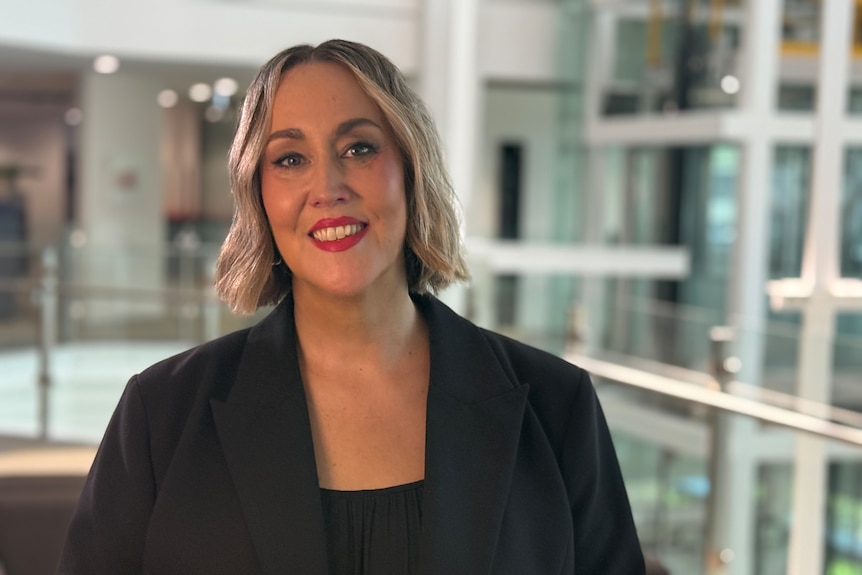 A woman with shoulder length blonde hair smiles at the camera.