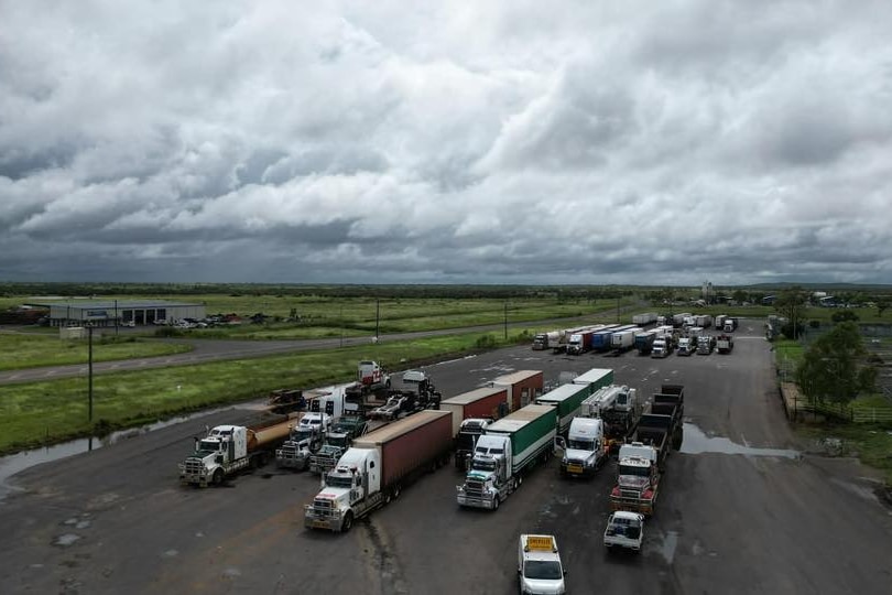 Trucks parked next to a field with storm clouds above 