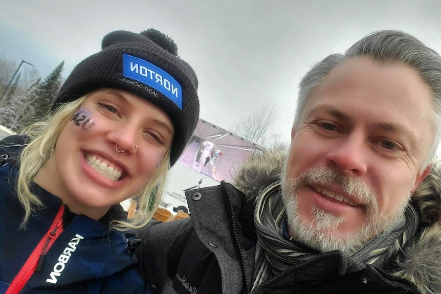 A young woman and man pose for a photo in cold weather.