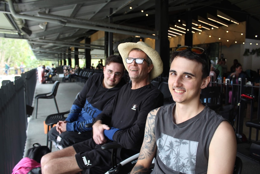 David Mobb smiles sitting between two younger men.