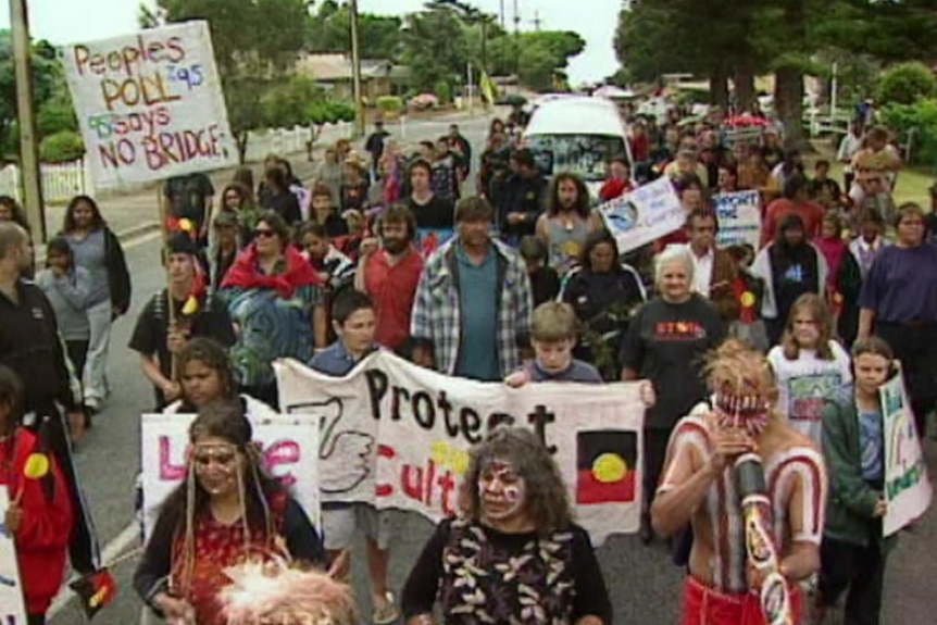 Group of indigenous people with signs march down a street.
