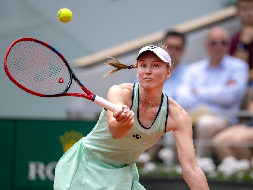 A female tennis player looks up at the ball as she extends her racquet to hit a forehand at the French Open.