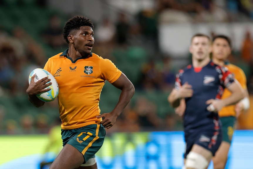 Wallace Charlie looks behind him as he runs with the ball tucked under his arm