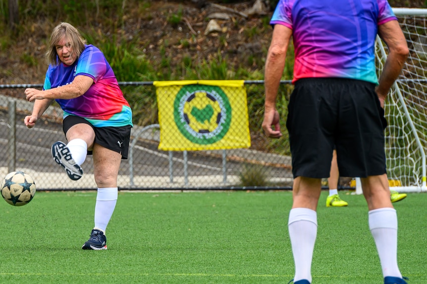 An older woman kicks the ball during a football game