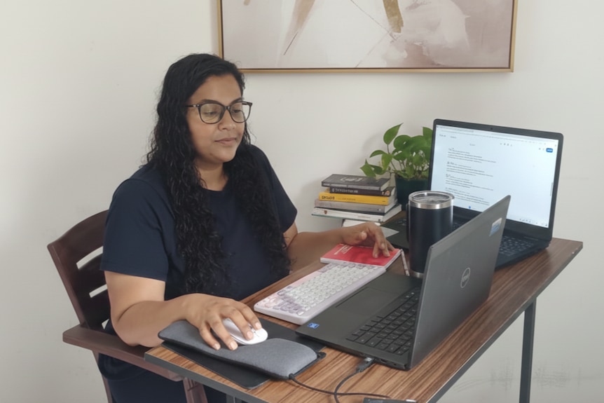 Dinethi Yasodara Jayarathna sits at a small home office desk in front of her compter.