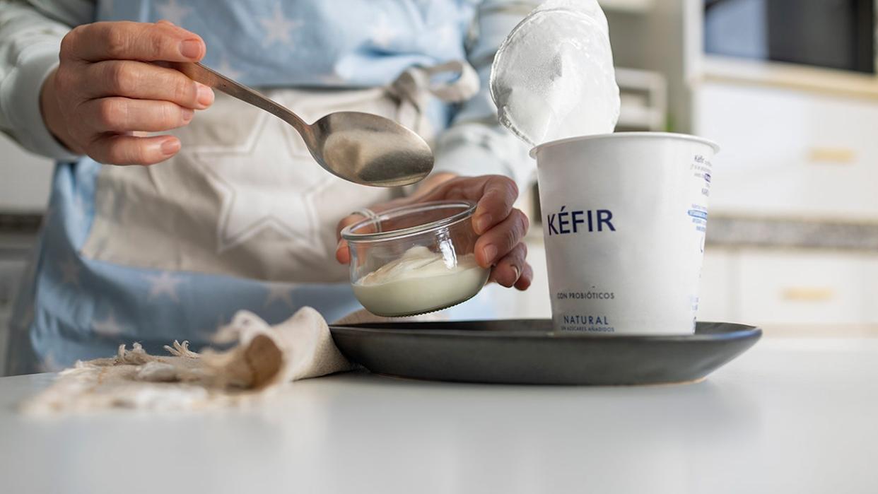 Close-up of a person spooning natural kefir from a small glass bowl.