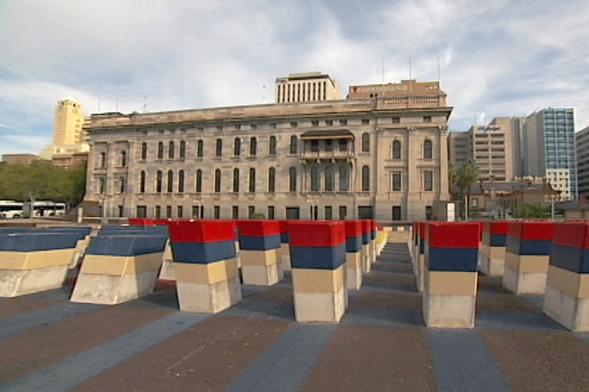 A series of coloured concrete sculptures with a 19th century stone buiding behind