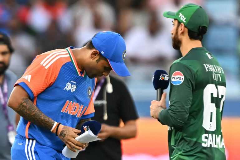 India's captain Suryakumar Yadav (L) walks after the toss as his Pakistan's counterpart Salman Agha watches before the start of the Asia Cup 2025 Super Four Twenty20 international cricket match between India and Pakistan at the Dubai International Stadium in Dubai on September 21, 2025. (Photo by Sajjad HUSSAIN / AFP)