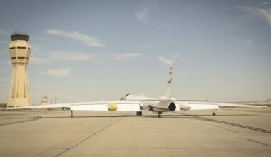 A NASA ER-2 aircraft taxis on the runway at Armstrong Flight Research Center with the control tower in the background.