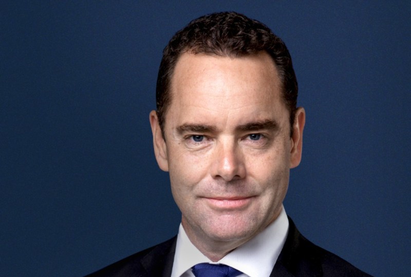 Professional headshot of a man in a suit against a dark blue background, conveying confidence and approachability.