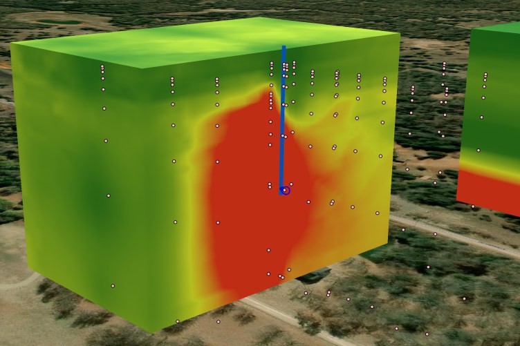 An animated image of a large cube sitting on top of land. The cube is mostly green with a large red cloud in the middle. A blue line runs from the top of the cube directly down into the red cloud.