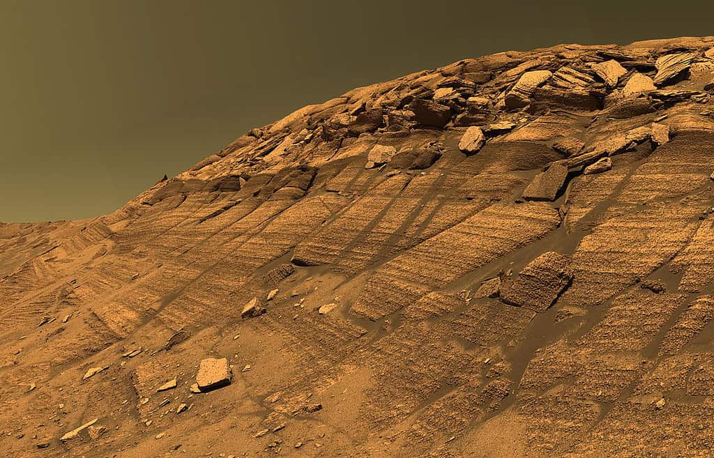 Mars surface with layered sedimentary rocks and scattered stones, showcasing the planet's geological.