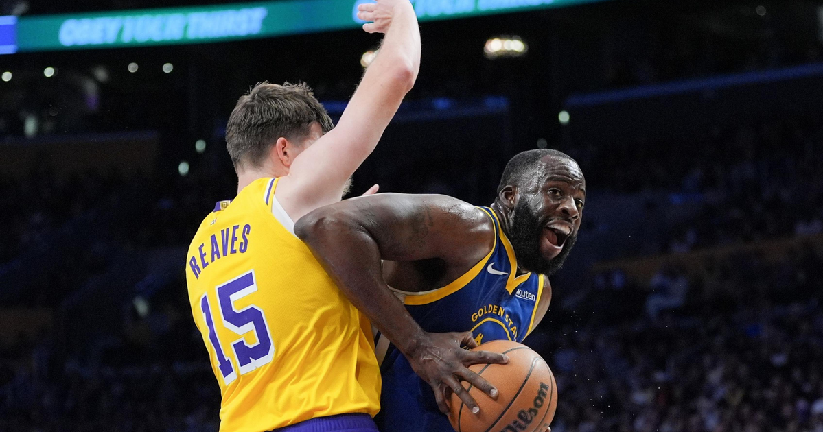 A basketball player in a blue Golden State Warriors jersey drives past a defender in a yellow Lakers jersey numbered 15 during a game.