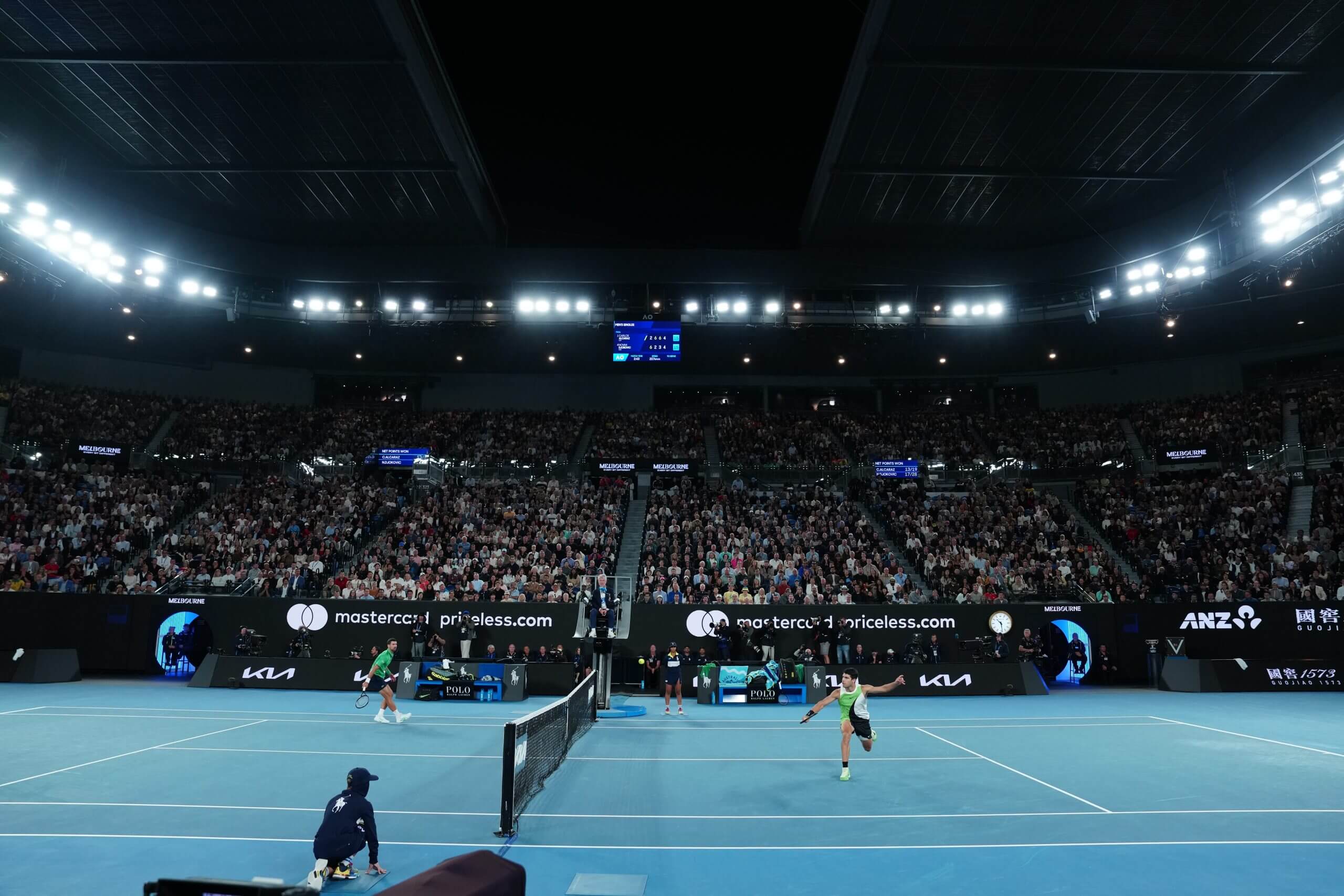 Carlos Alcaraz and Novak Djokovic duel at the net on Rod Laver Arena.