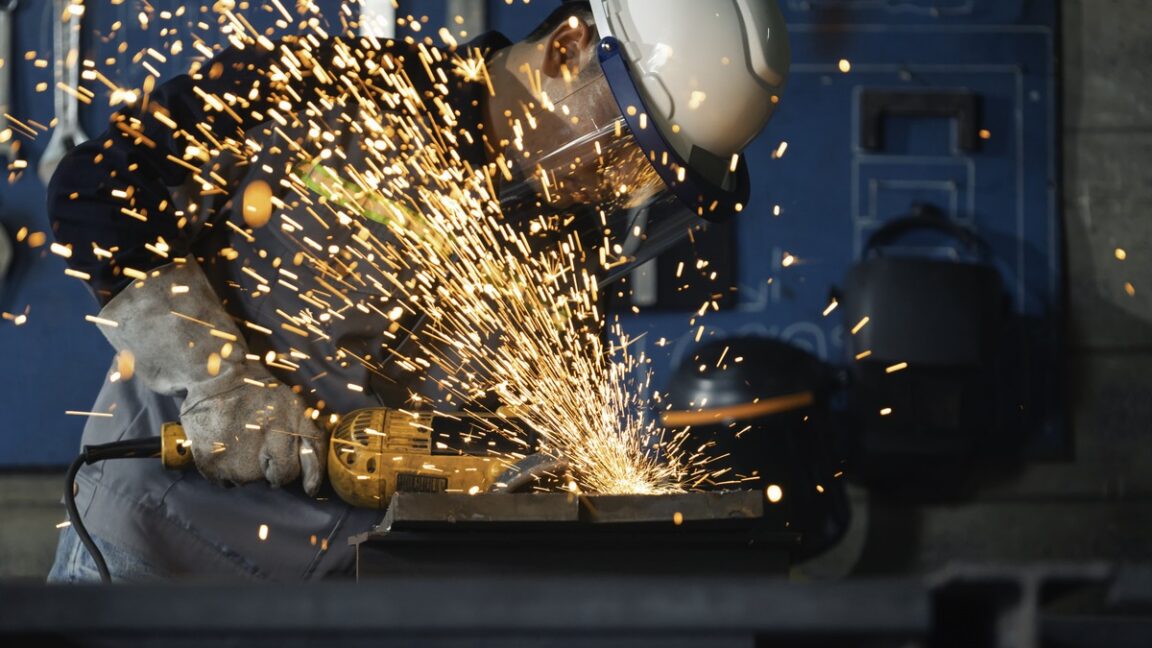 A man using a metal grinder causing sparks to fly.