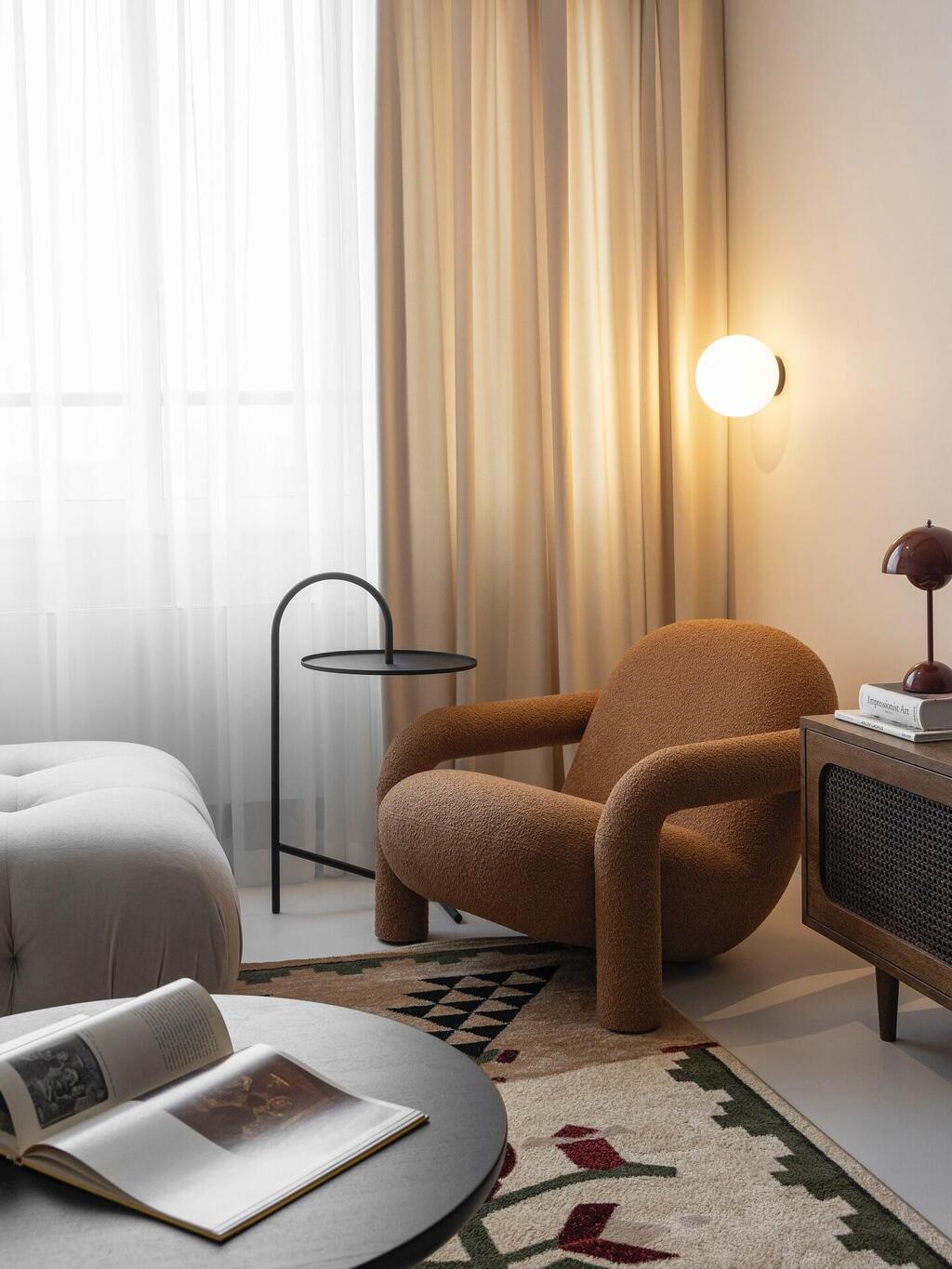A brown bouclé armchair and soft wall lighting, both by Ukrainian brand Diza (Photo: Courtesy of Prat Living) כורסה בבד בוקלה בגוון חום ותאורה רכה במרכז הקיר diza אוקראינה