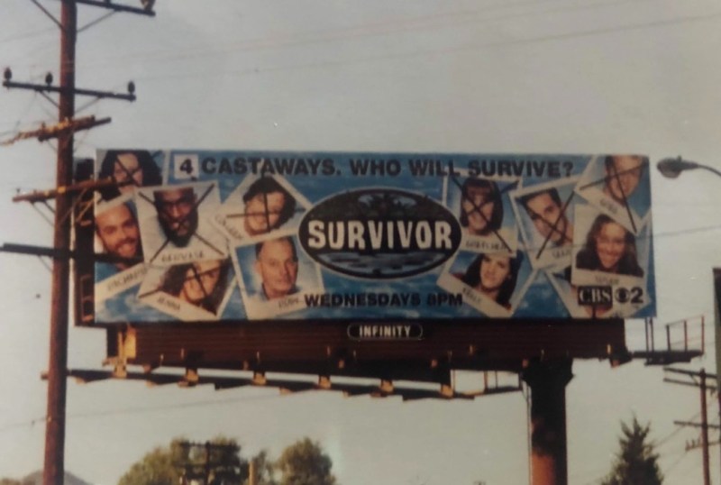 Billboard promoting the TV show Survivor, featuring the tagline "4 Castaways. Who Will Survive?" with images of contestants, some crossed out, and airing details for Wednesdays at 8 PM on CBS.