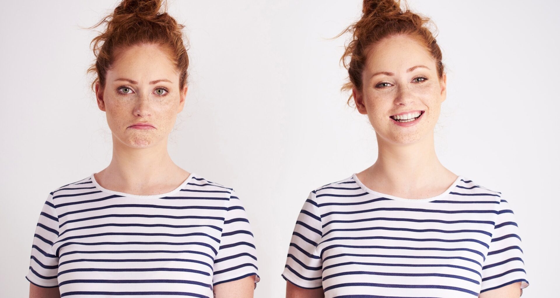 Young women twins standing next to each other. One is smiling and the other is grumpy