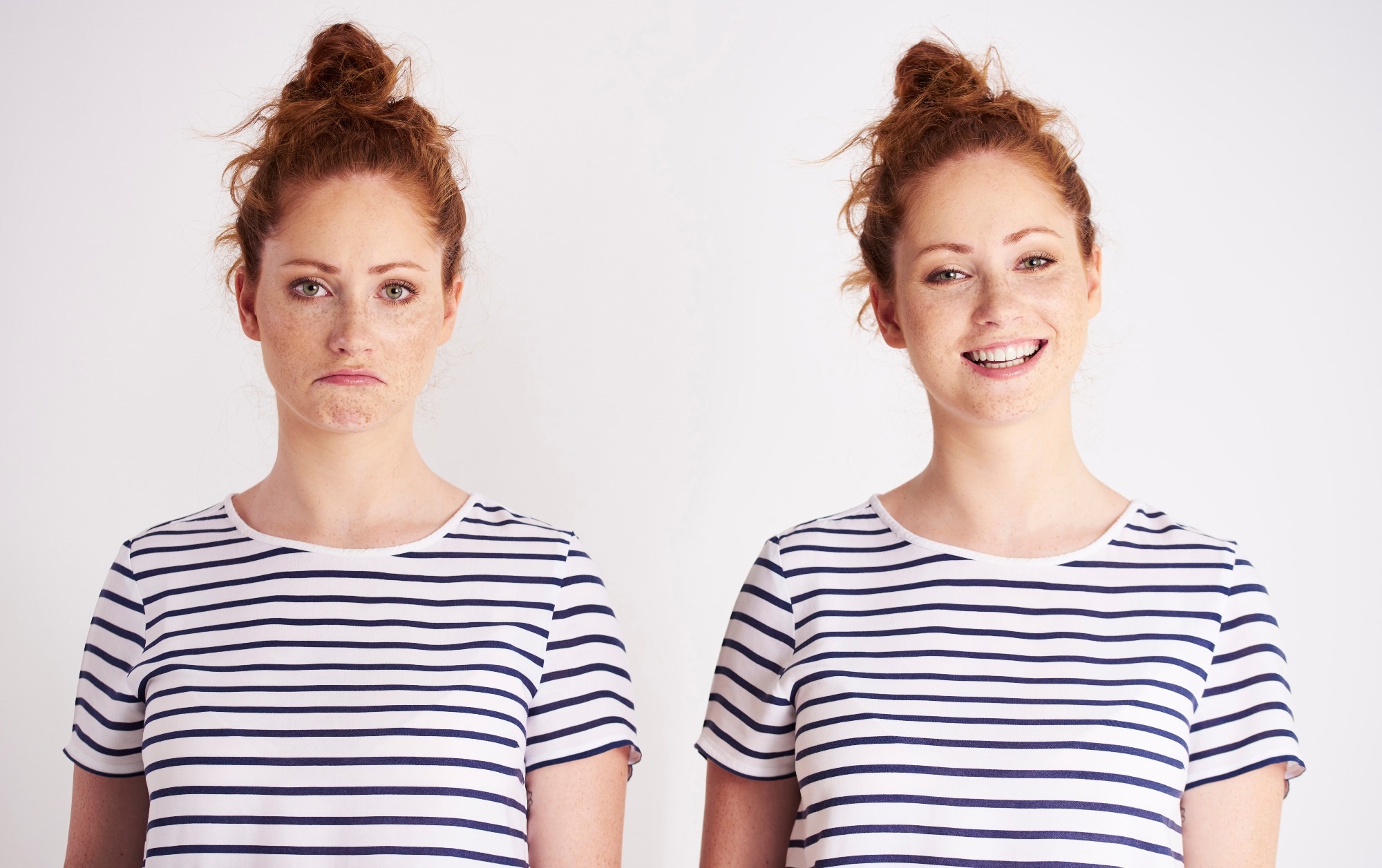 Young women twins standing next to each other. One is smiling and the other is grumpy