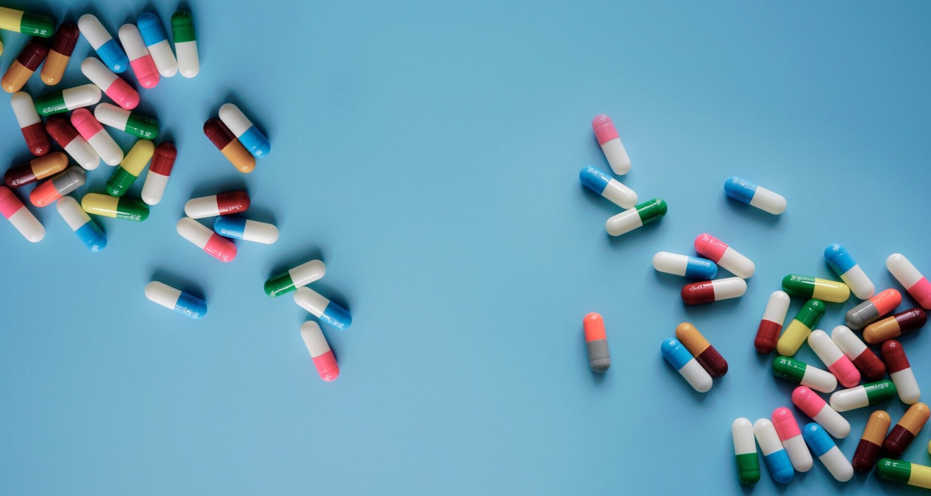 Top view colorful antibiotic capsule pills on blue background.