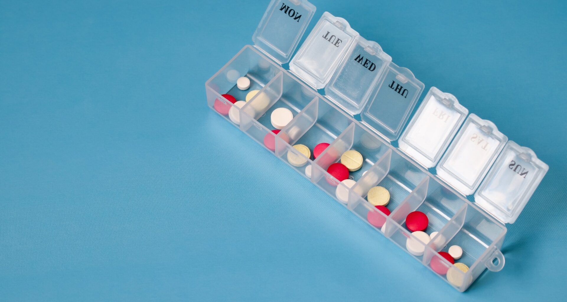 Daily pill box with various pills and tablets for managing medication schedule. medical background with space for text