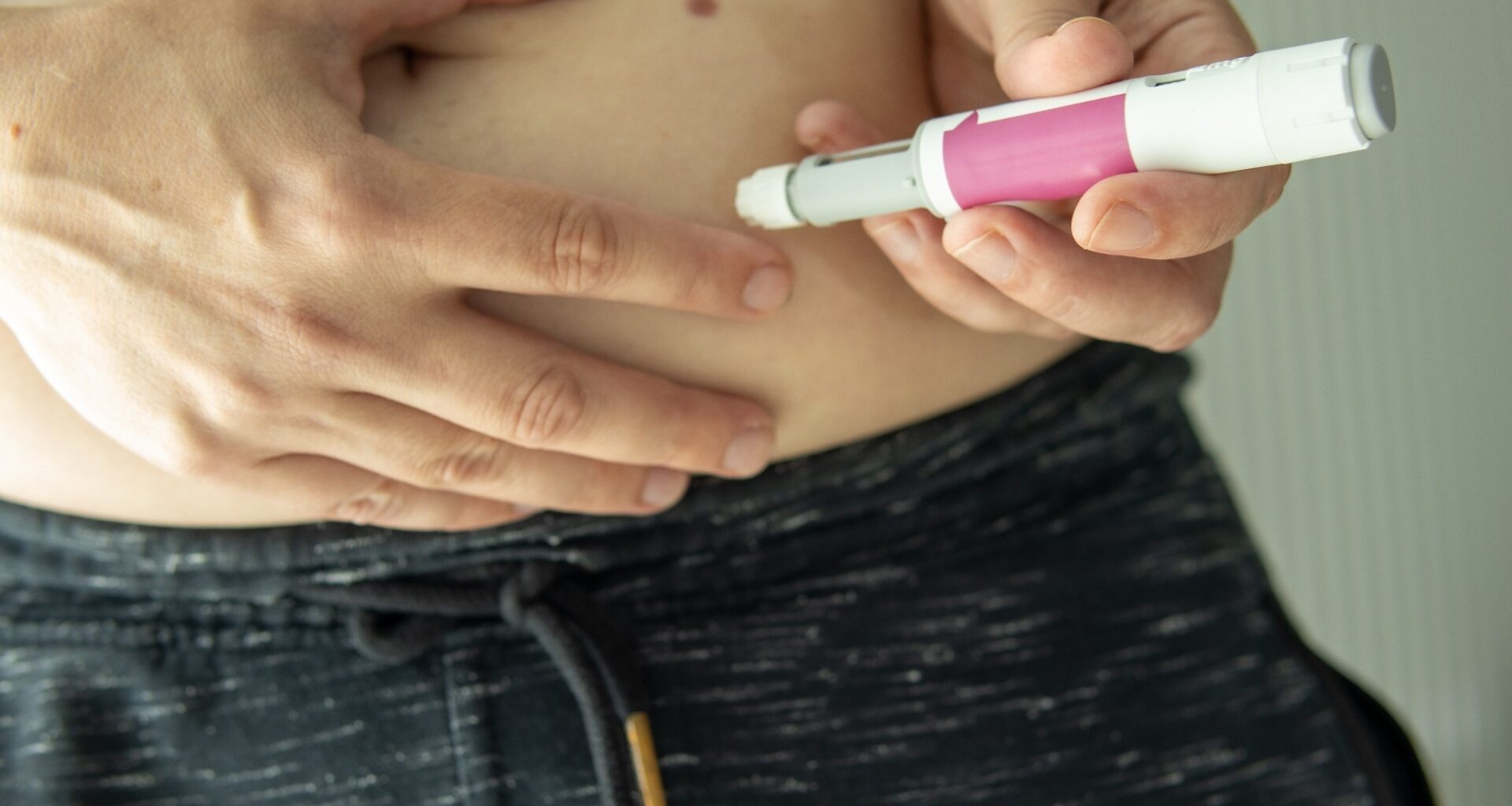A person prepares to inject semaglutide with a pen into their abdomen.