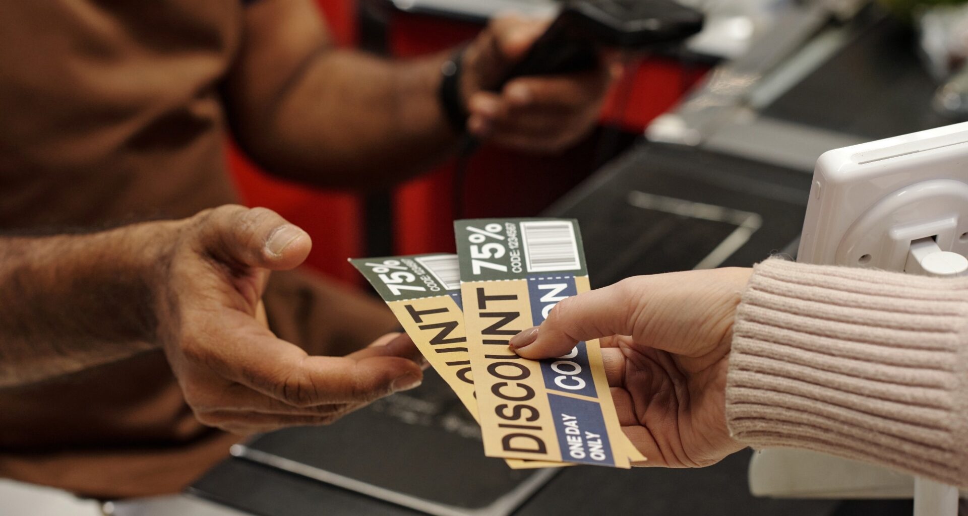 Closeup of female hand holding discount coupons for best deals and giving to cashier at supermarket checkout line