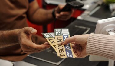 Closeup of female hand holding discount coupons for best deals and giving to cashier at supermarket checkout line