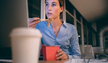 Businesswoman sitting working in office late in the nightre and eating noodles sitting at her desk.