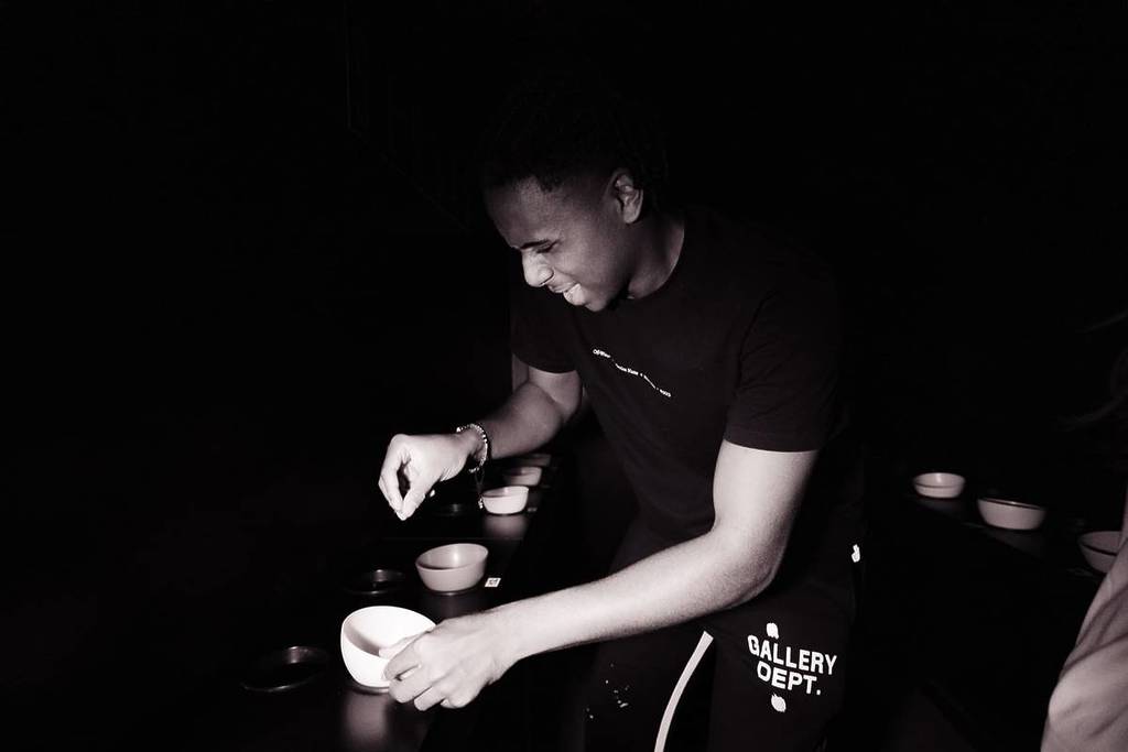 A young man holding a bowl in his hand in the pitch-black Taste Lab at SENSAS.