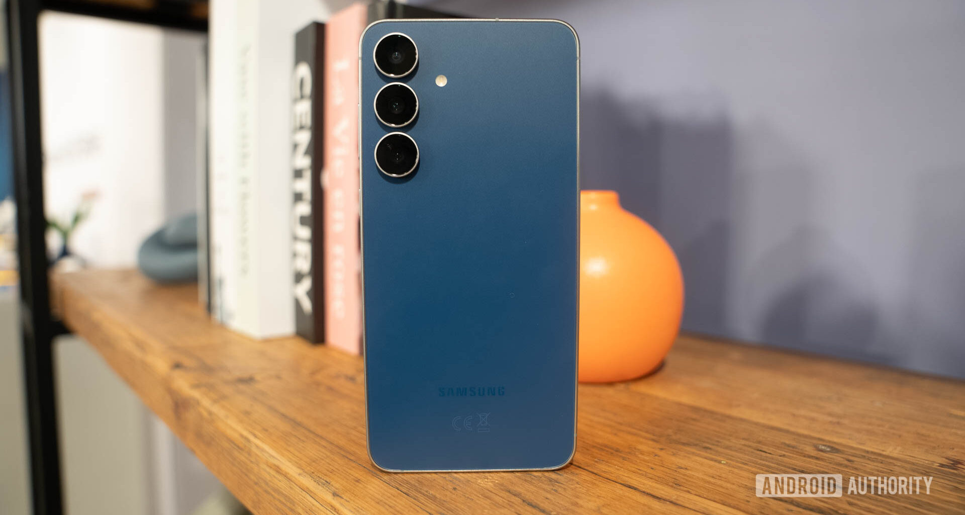 Samsung Galaxy S25 FE in Navy standing on book shelf