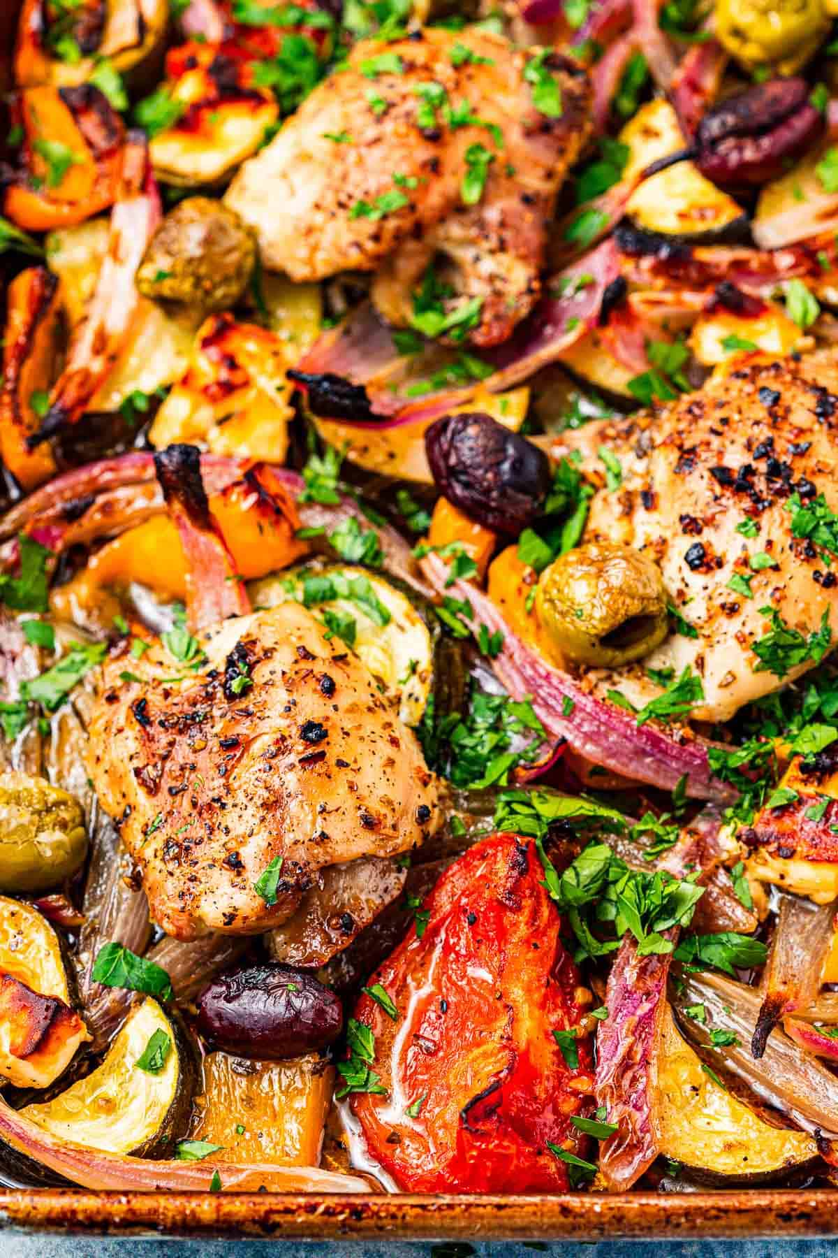 close up of baked Greek sheet pan chicken with vegetables.