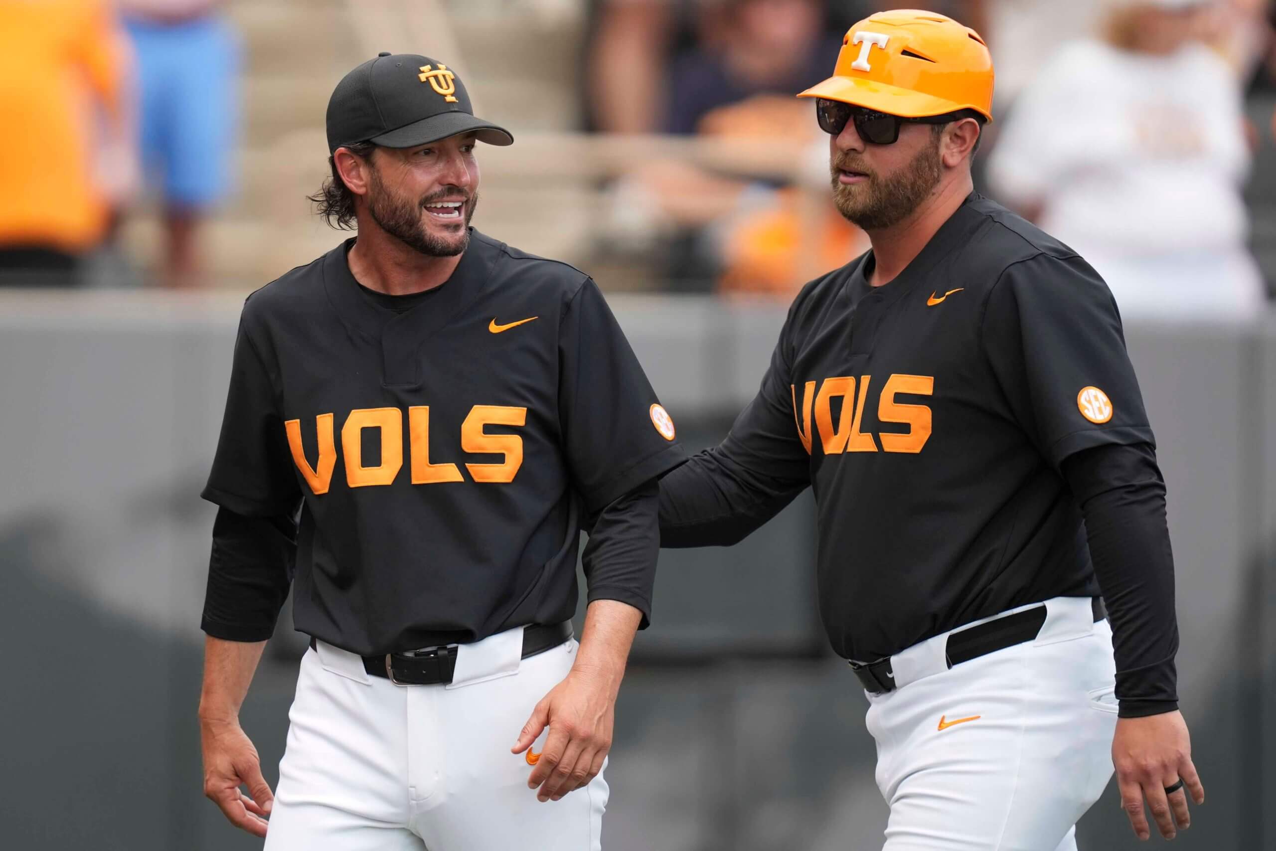 Tennessee assistant coach Ross Kivett leads head coach Tony Vitello back to the dugout.