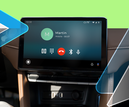 A car dashboard display running Android Auto during a phone call, with the Android Auto logo overlaying.