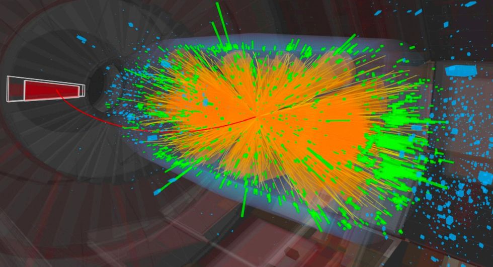 A colorful visualization shows many particle tracks radiating outward from a collision point.