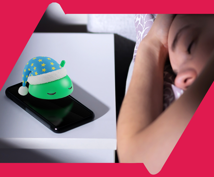 A person sleeping in bed with a phone on the nightstand showing a sleeping android mascot wearing a nightcap.