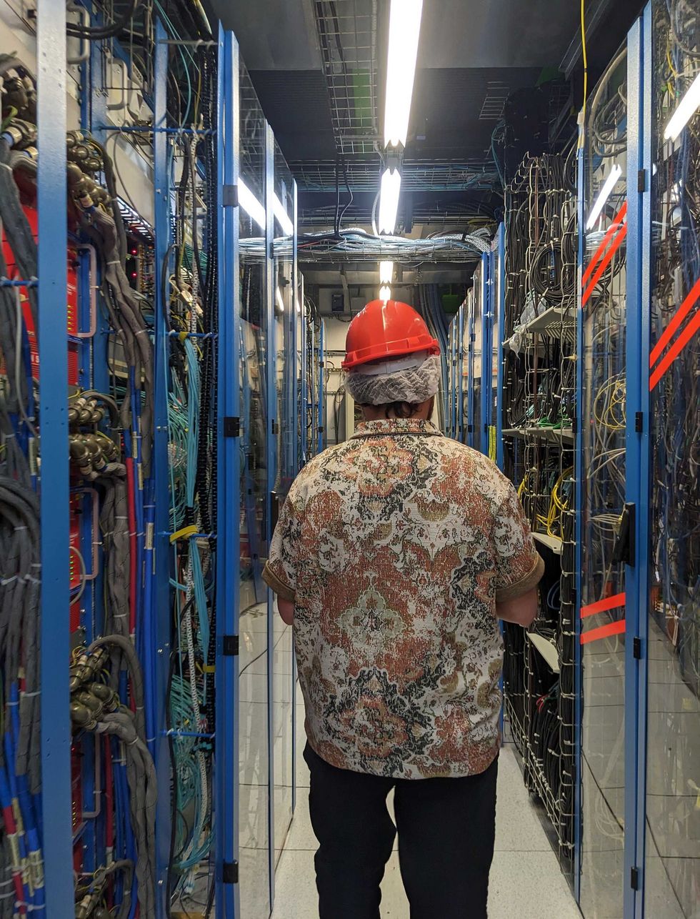 a person wearing a hard hat walks down an aisle.