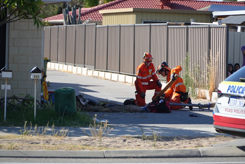 Two SES crew members examining the scene of a car v house
