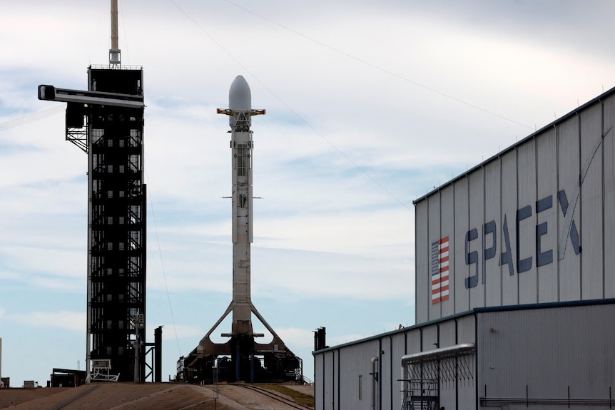 A grey building labelled SpaceX with a space rocket next to it 
